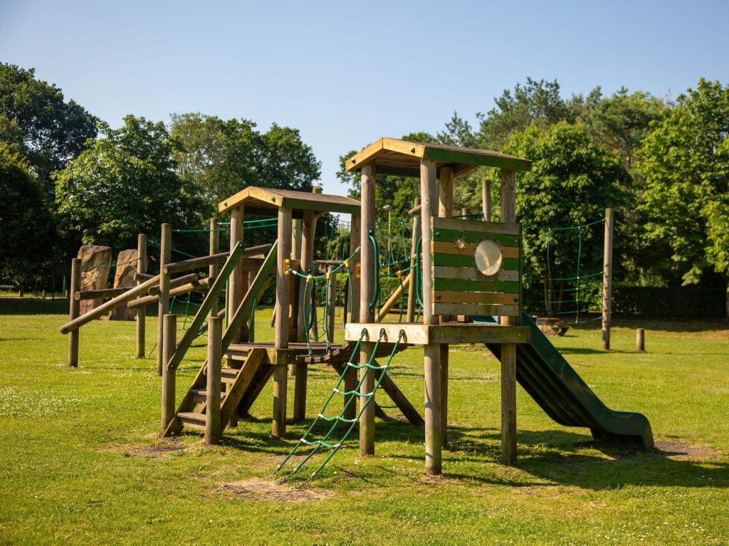 Image of play equipment including wooden towers, bridge, rope ladders and slide, at Ancells Farm Park