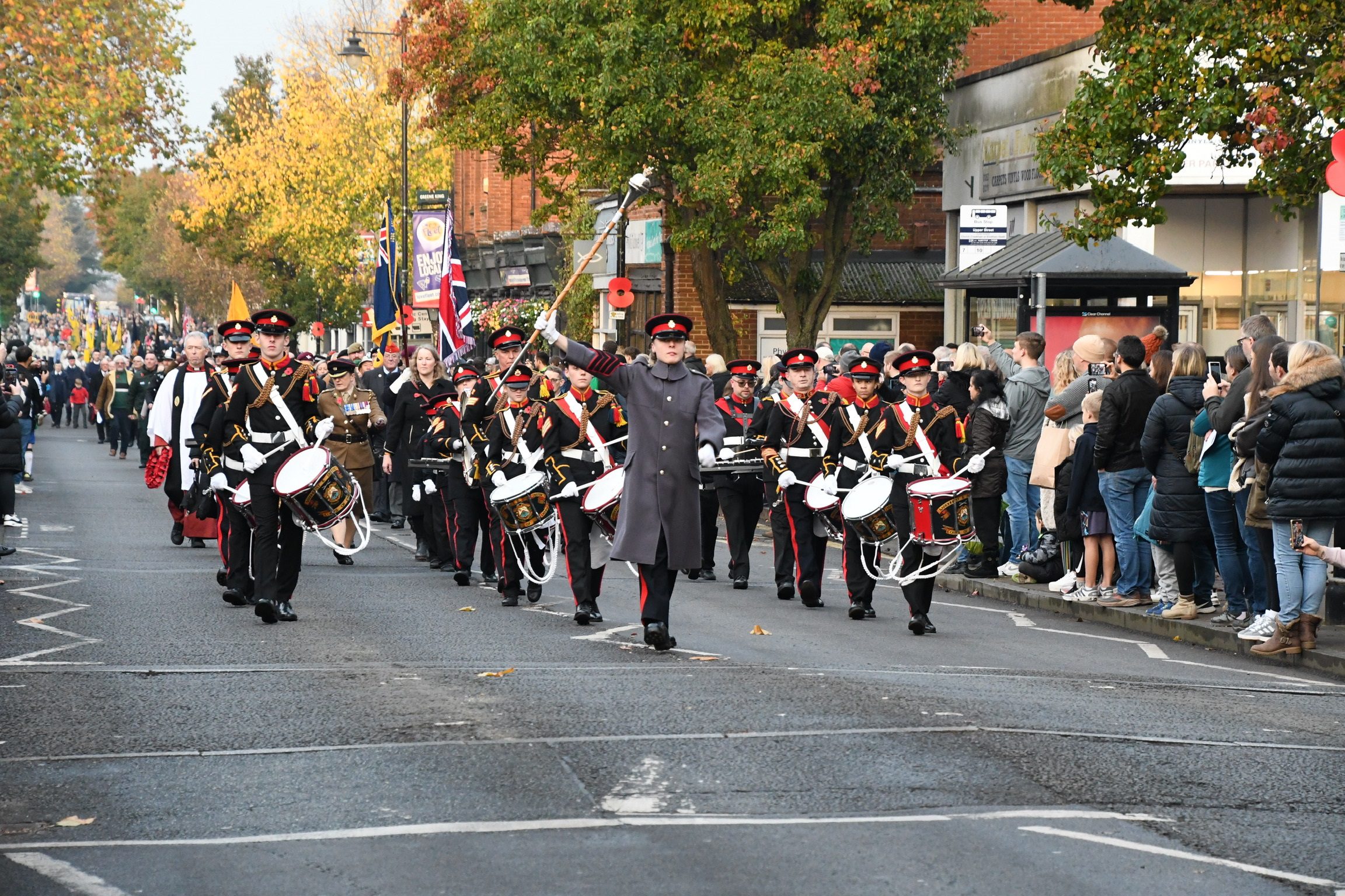 Image of remembrance day parade down the highstreet with a corp of drums leading the parade