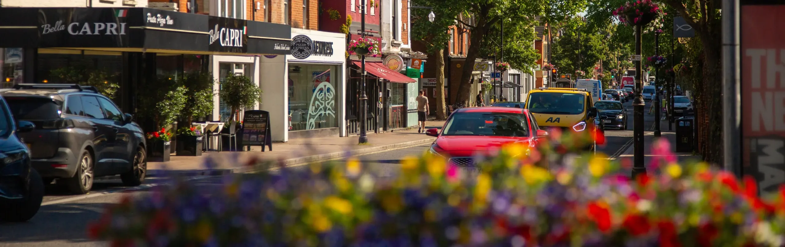 Image of fleet high street showing restaurants, cars and bright floral displays