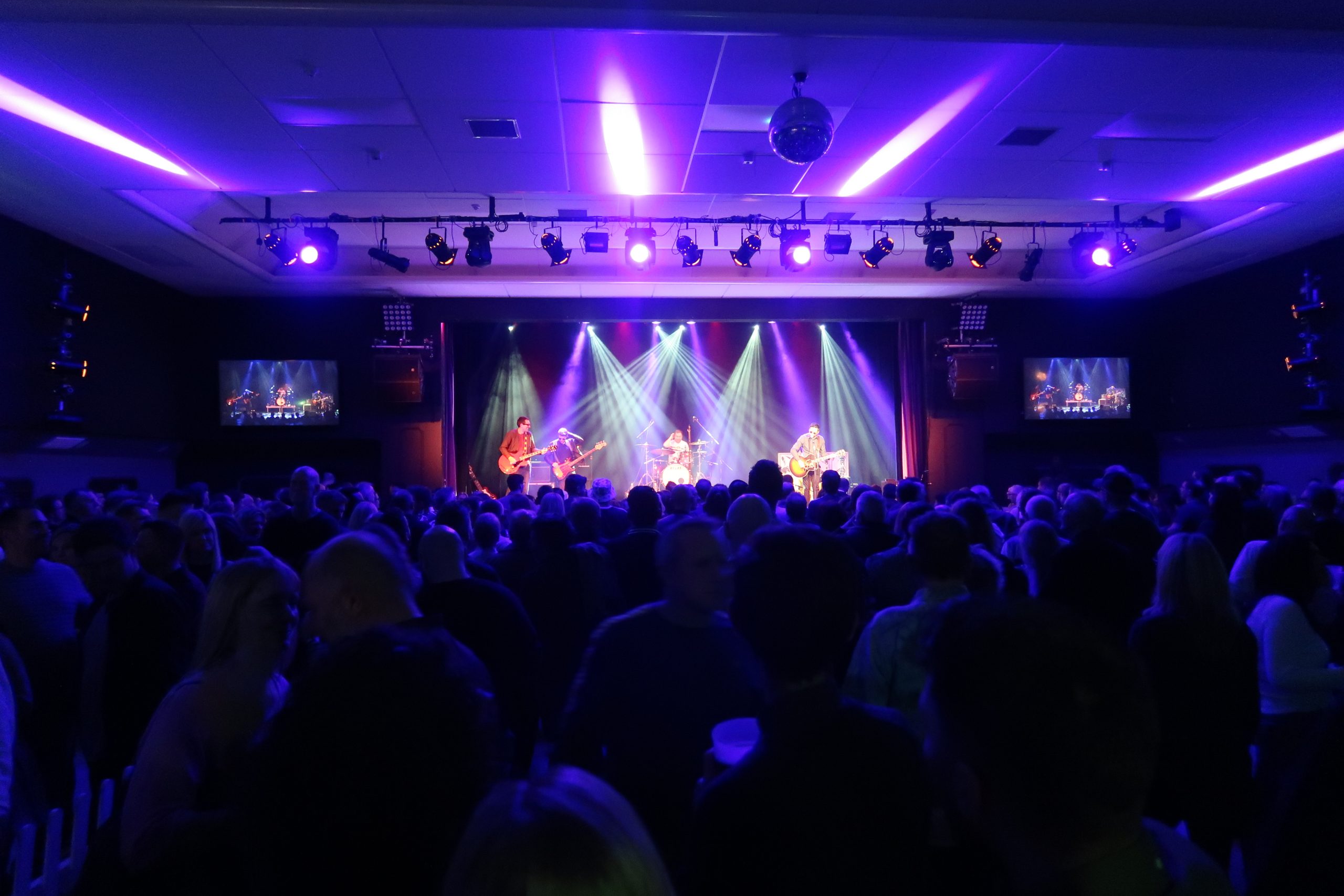 Image of an show at the harlington - a packed hall with a band on stage